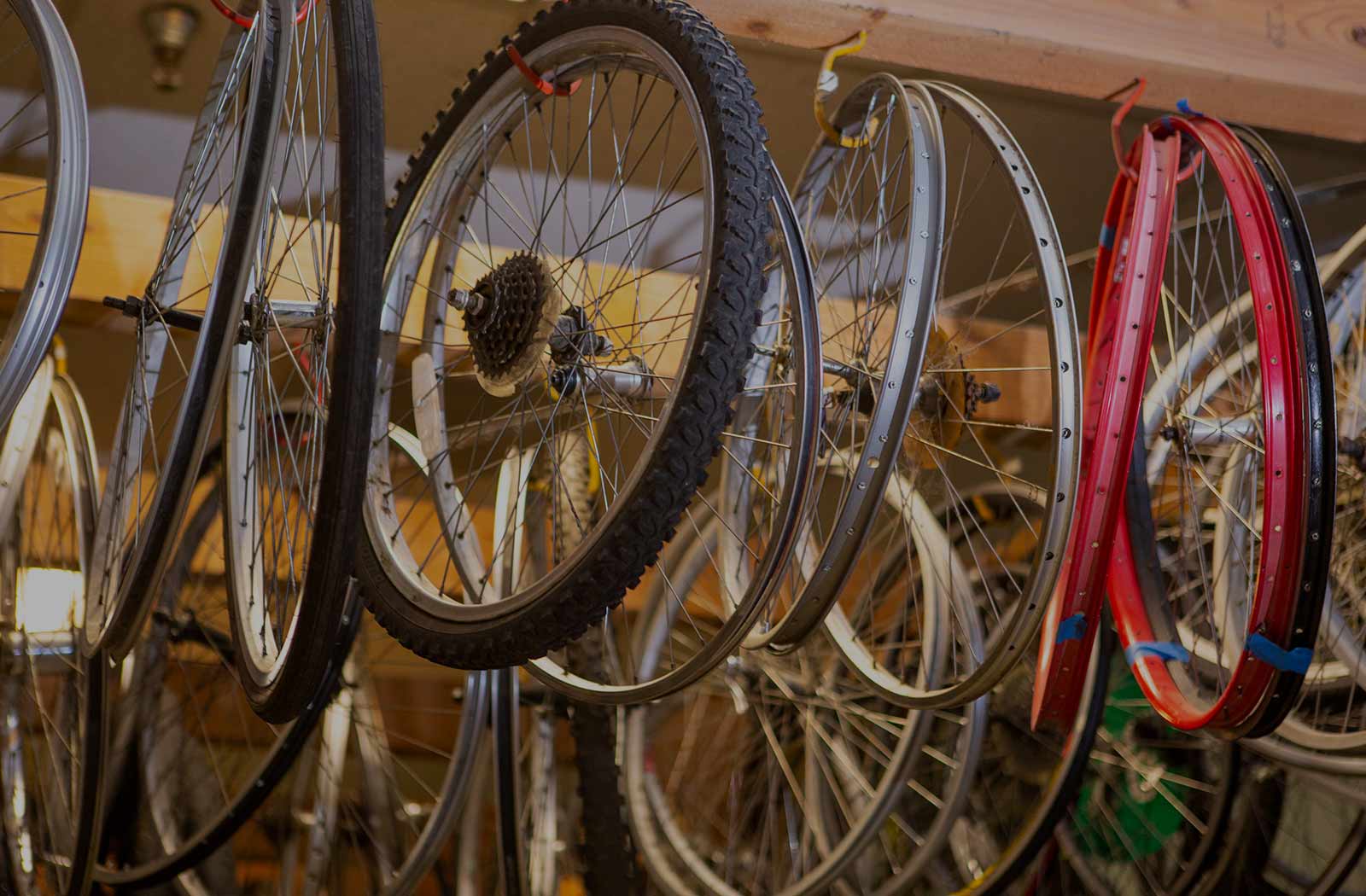 Bike wheels hangin from wooden rafter in the Toy Project Bike Shop