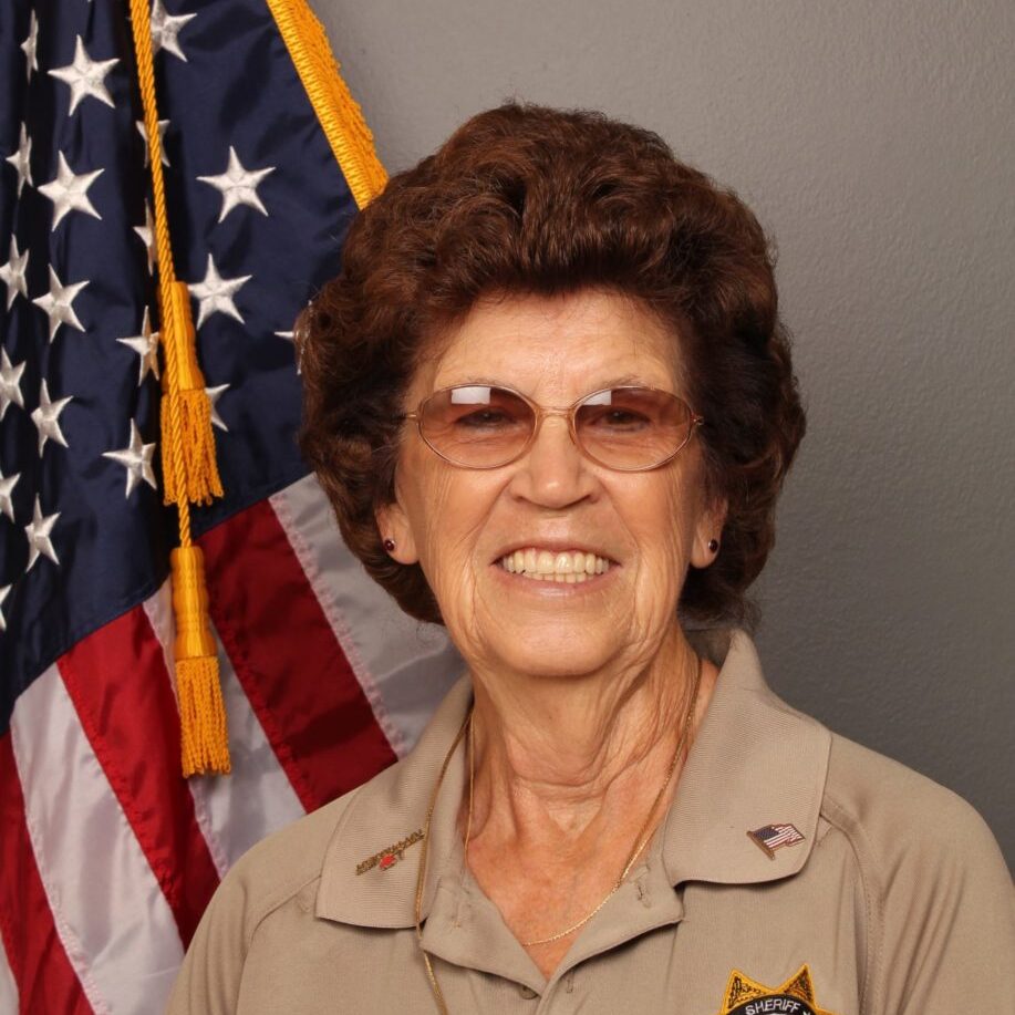 color portrait photograph of Rose Tarver in her Sherrif's Brown Polo with the US flag in the background
